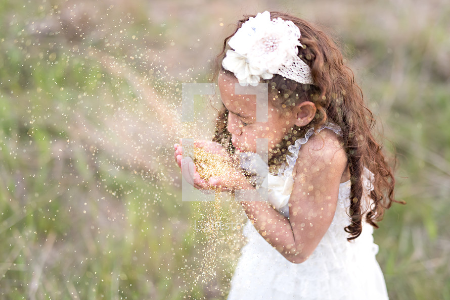 a girl child blowing glitter 