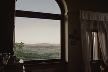 view of hills and mountains out a window in Italy 