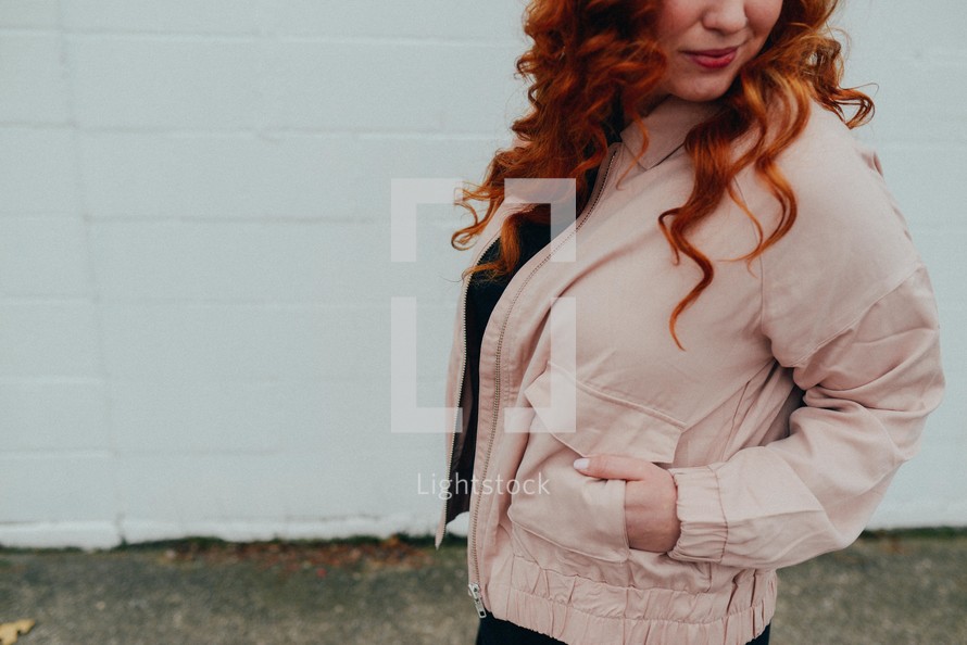 a redhead woman with her hands in her pockets 
