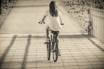 girl riding a bicycle across a bridge 