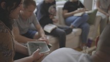 Co-ed, multi-generational home group prays in a living room.