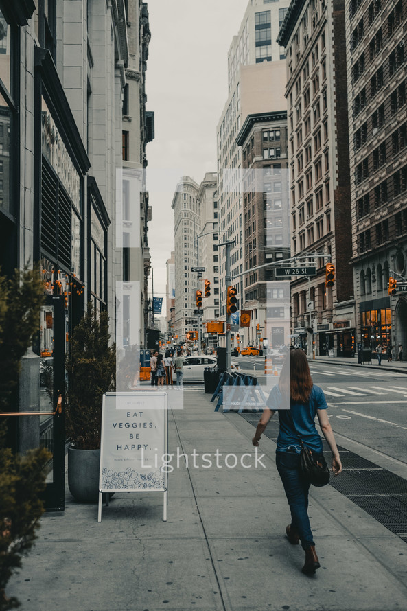 a woman walking down a city sidewalk 