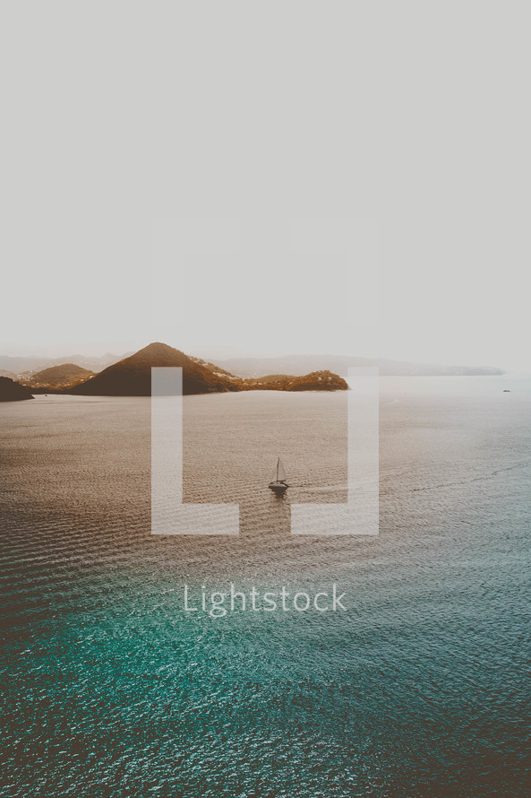 aerial view over an island and sailboat 