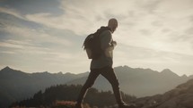 Man with backpack hiking in the mountains at sunset (or sunrise)