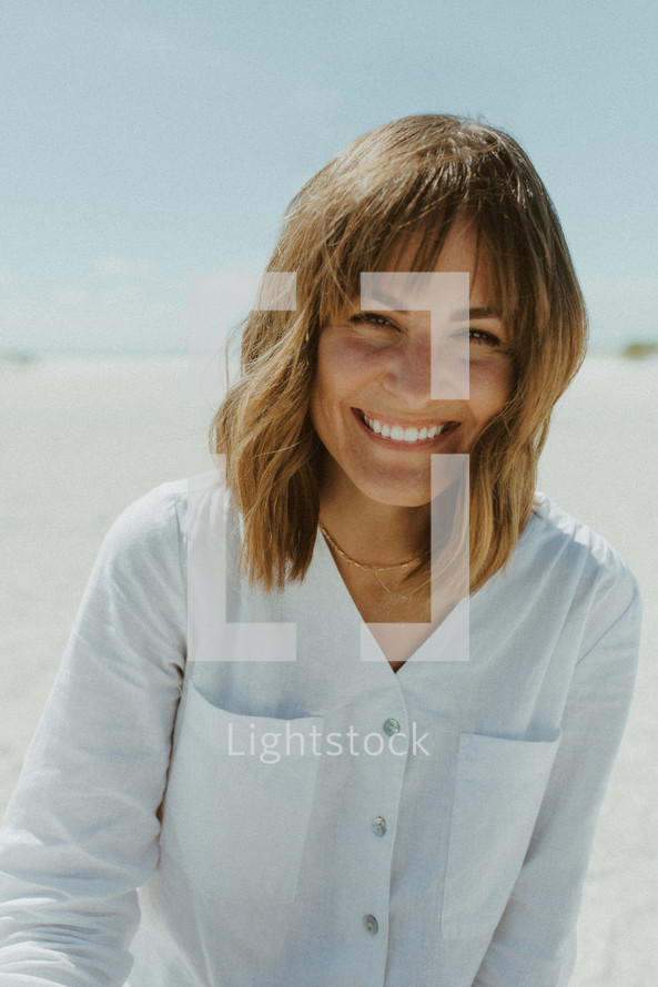a smiling woman sitting on a beach 