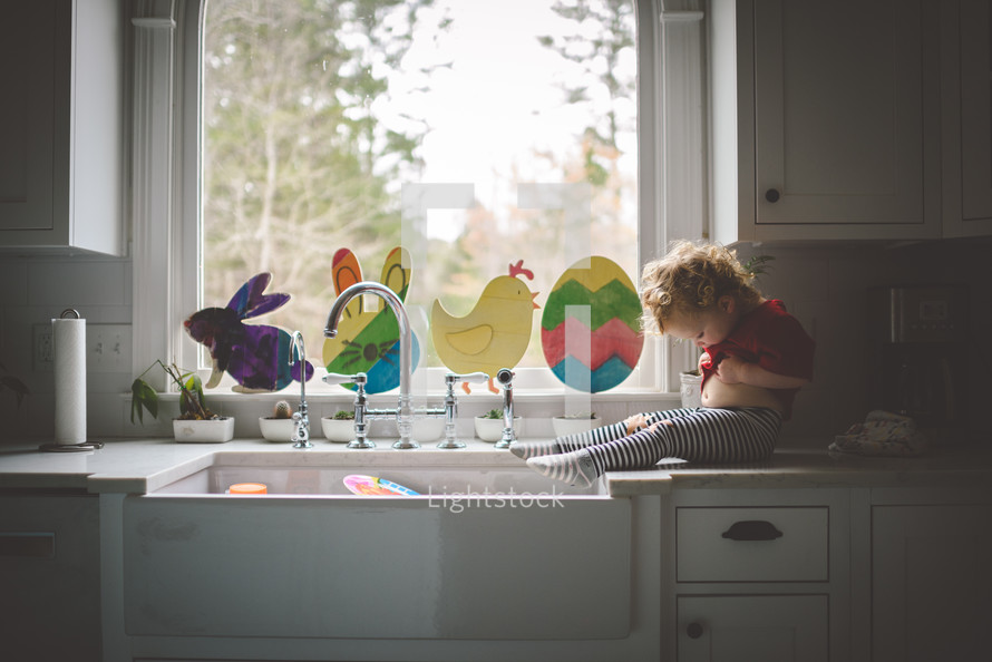 toddler girl sitting by a sink 