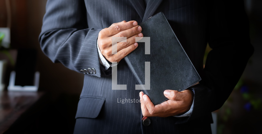a man in a suit holding a Bible 