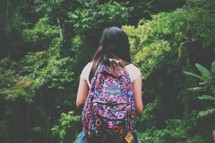 a teen girl with a backpack outdoors in a forest 