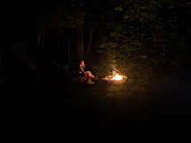 sitting by a campfire in a forest 