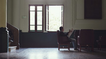 a man reading a newspaper in a waiting room 