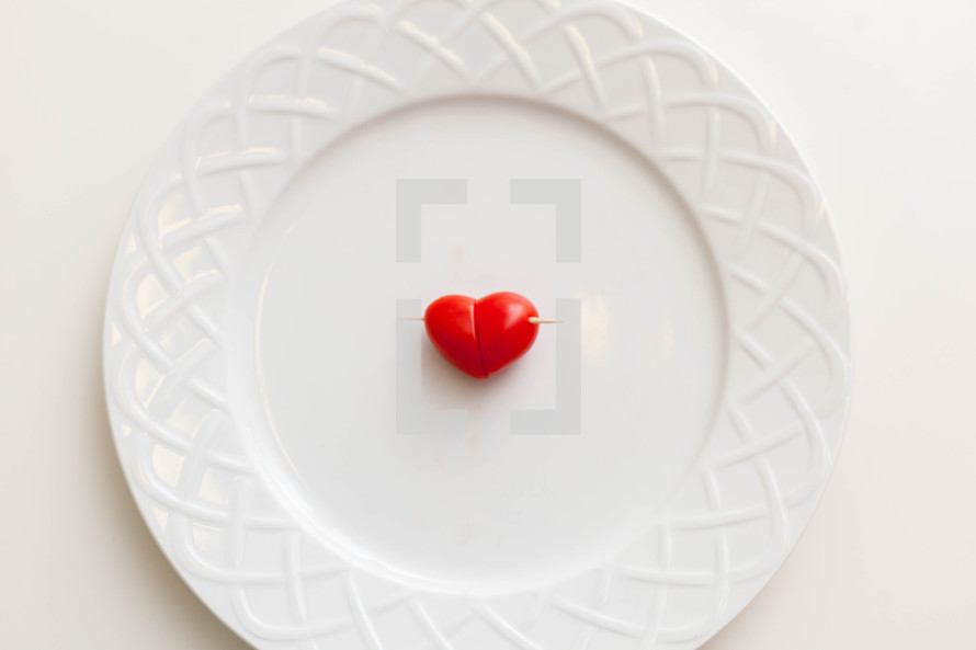 A heart shaped tomato h'or d'oeuvre on a white plate.