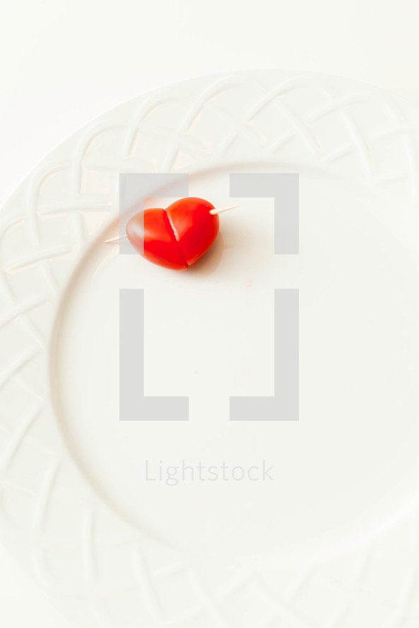 A heart shaped tomato on a white plate.