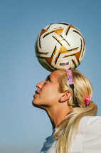 soccer player balancing a ball on her head
