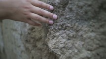 A person runs fingers along a stone wall