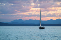 A sailboat on a lake surrounded by mountains.