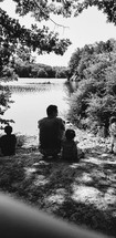 family sitting by a lake shore 