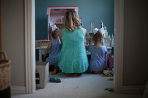 mother playing dollhouse with her daughters 