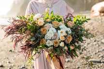 bride with a flower bouquet on a beach 
