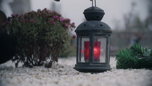 Red candle lantern on the grave. Close-Up