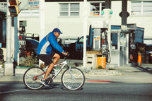a man riding a bicycle past a gas station 