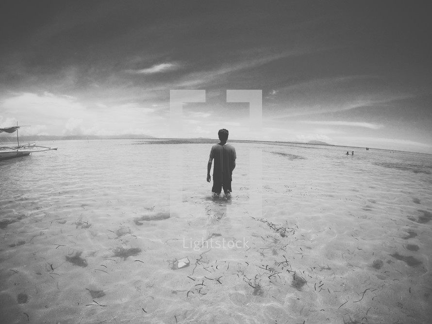 a man standing knee deep in ocean water 