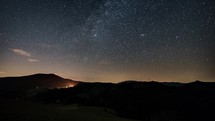 Stars with milky way galaxy moving in starry night sky over mountains silhouette in rural nature Astronomy Time lapse