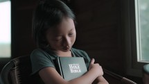 Girl praying while holding her Bible