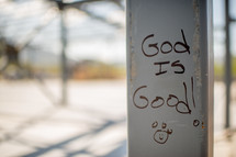 "God is good" handwritten on a metal pole.