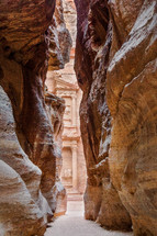view of through an opening in red rock cliffs Petra, Jordan 