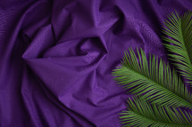 Palm leaves on a purple cloth background 
