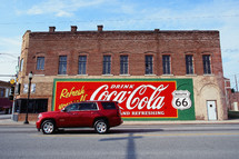 car driving down a small town downtown road and coca-cola sign 