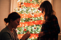 mother and daughter decorating a Christmas tree 