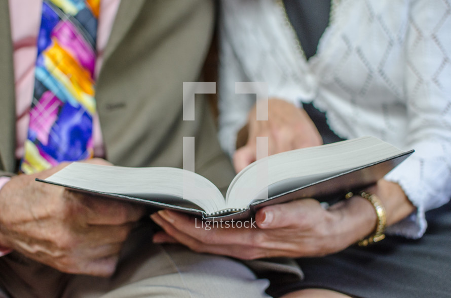 an elderly couple reading a Bible together 