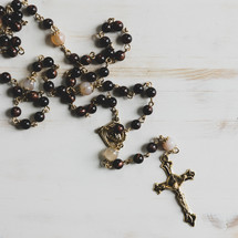 rosary beads on a white wood background 