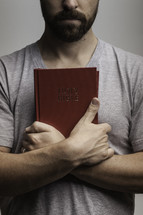 man holding a Bible against his chest 