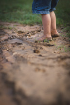 child's bare feet in mud