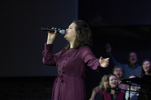 a worship leader and choir leading a congregation in song 