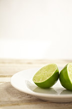  A lime sliced in half - sitting on a plate.