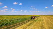 Aerial shot of tractor on harvest fields in summer day with blue sky. Food industry concept.
