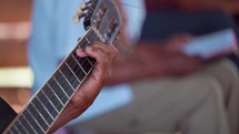 Close up of man's hand playing guitar in small church service in Honduras