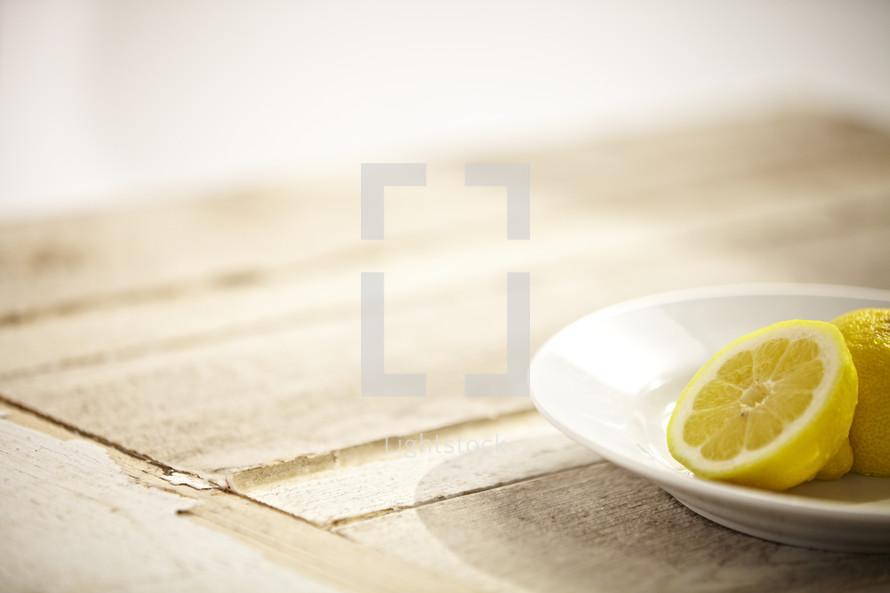 Two halves of a lemon sitting on a plate on a wooden table