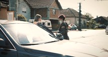 two women wearing face masks talking in front of a car