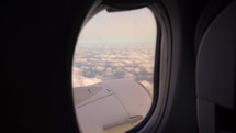 Airplane wing is seen through its window while flying. Airplane, Aircraft. Traveling by air.	
