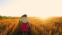 Woman in red dress running in golden wheat field