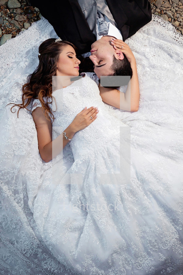 portrait of a bride and groom lying on the ground 