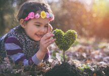 girl planting a heart-shaped tree and dreaming of a beautiful future