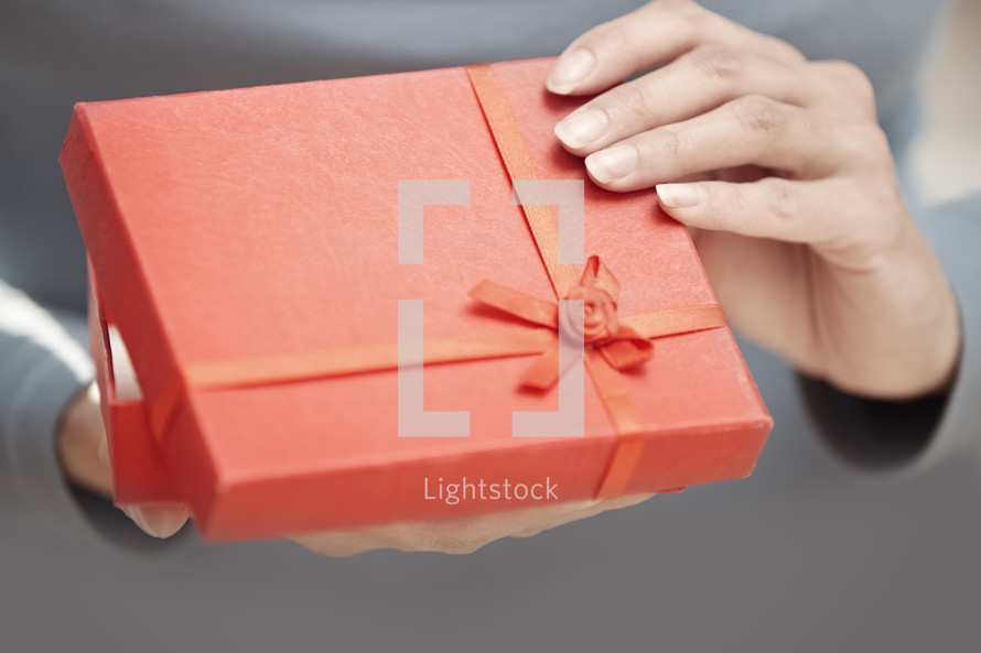Hands of woman opening red gift box