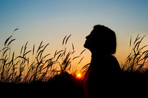 profile of a woman in a field at sunset 