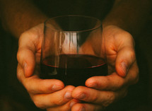 Hands holding a glass of wine.