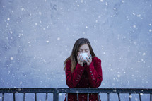 a teen girl drinking a mug in the snow 